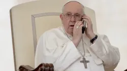Le pape François prend un appel téléphonique lors de l'audience générale du 17 mai. | Daniel Ibáñez/EWTN News / 