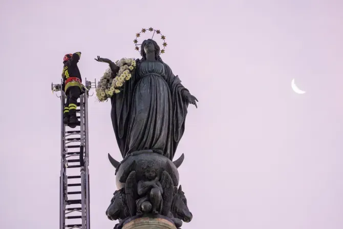 Un pompier monte une longue échelle jusqu'au sommet d'une colonne de près de 40 pieds de haut pour rendre hommage à l'aube à la Sainte Vierge avec une couronne de fleurs, le 8 décembre 2023. | Crédit photo : Daniel Ibanez/CNA