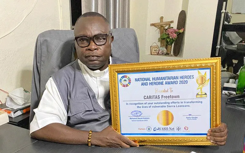 Le père Peter Konteh avec le prix reçu par Caritas Freetown lors de la commémoration de la Journée mondiale de l'aide humanitaire le 19 août. / Caritas Freetown