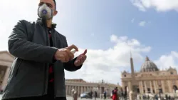 Un pèlerin de Russie porte un masque et utilise du désinfectant pour les mains devant la basilique Saint-Pierre au Vatican le 6 mars 2020. / Daniel Ibáñez/CNA.