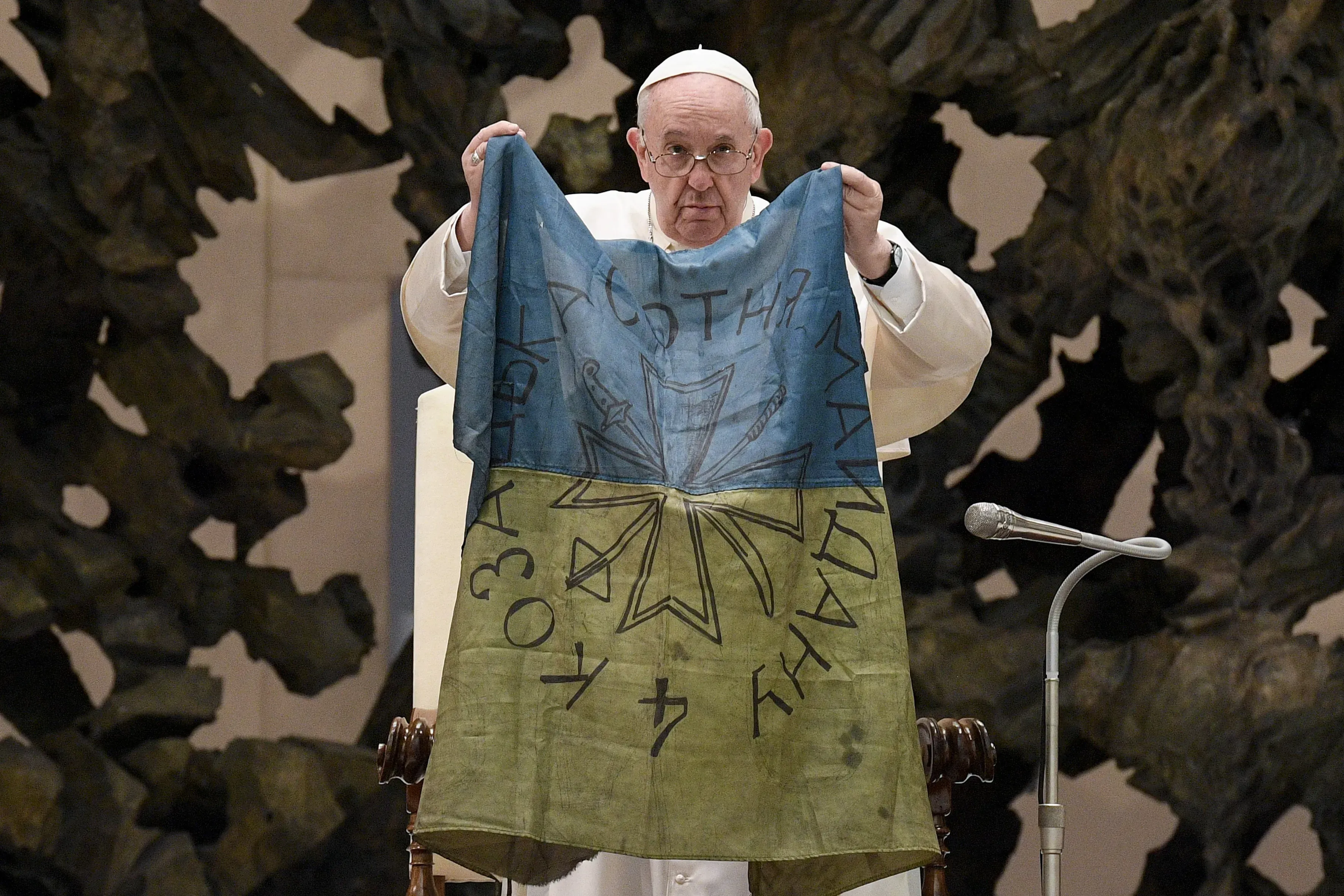 Le pape François brandit un drapeau qui, selon lui, lui a été apporté de "la ville martyre" de Buca, en Ukraine, lors de son audience générale du 6 avril 2022. Vatican Media