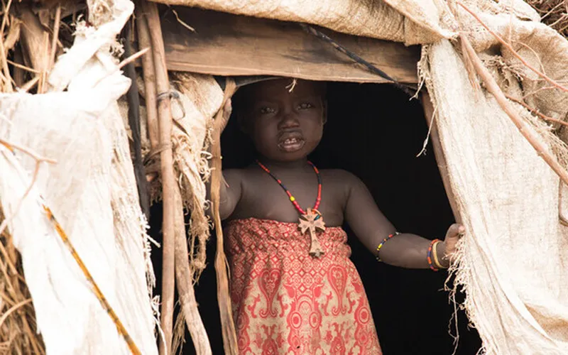 Une petite fille de la tribu Desanetch en Éthiopie pose à l'entrée d'une maison de fortune/ Crédit : Aide à l'Église en détresse