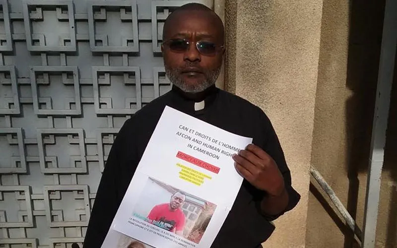 Le Père Ludovic Lado tenant un poster des personnes détenues à la suite de la crise anglophone. Crédit : P. Ludovic Lado