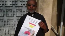 Le Père Ludovic Lado tenant un poster des personnes détenues à la suite de la crise anglophone. Crédit : P. Ludovic Lado / 