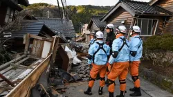 Des pompiers inspectent des maisons en bois effondrées à Wajima, dans la préfecture d'Ishikawa, le 2 janvier 2024, au lendemain d'un important séisme de magnitude 7,6 qui a frappé la région de Noto dans la préfecture d'Ishikawa. | Crédit photo : KAZUHIRO NOGI/AFP via Getty Images / 
