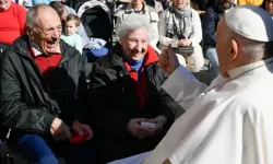 Le pape François salue un couple de personnes âgées lors de l'audience générale sur la place Saint-Pierre au Vatican. / 