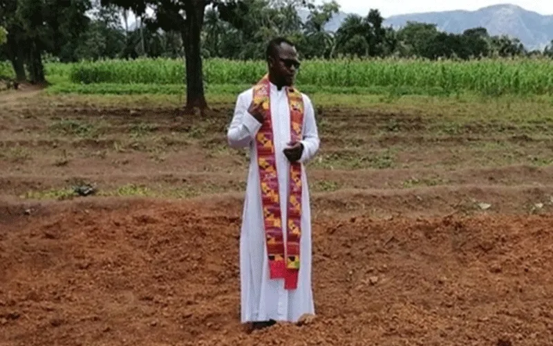 Le père Sam Ebute prie sur une fosse commune au Nigeria. Aide à l'Église en détresse (AED)