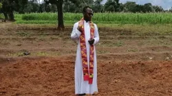 Le père Sam Ebute prie sur une fosse commune au Nigeria. / Aide à l'Église en détresse (AED)