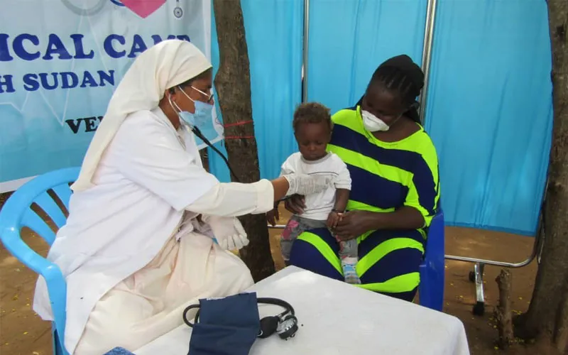 Un membre de la Compagnie des Filles de Marie Immaculée et des collaborateurs fournissant une assistance sanitaire à un petit enfant. ACI Afrique