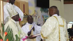 Mgr John Mbinda présente le Livre des Évangiles aux diacres nouvellement ordonnés. Crédit : ACI Afrique / 